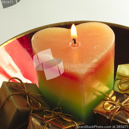 Image of heart candle and presents in a red glass bowl