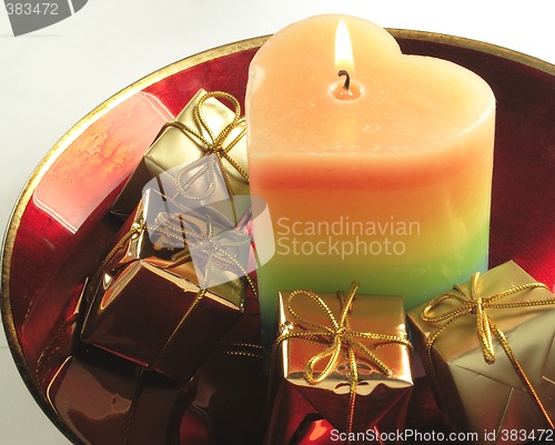 Image of heart candle and presents in a red glass bowl