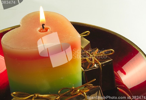 Image of heart candle and presents in a red glass bowl