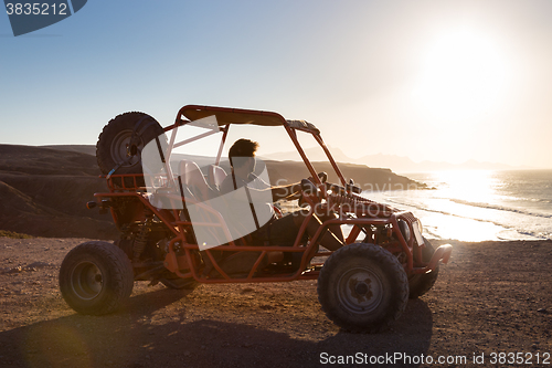 Image of Man driving quadbike in sunset.