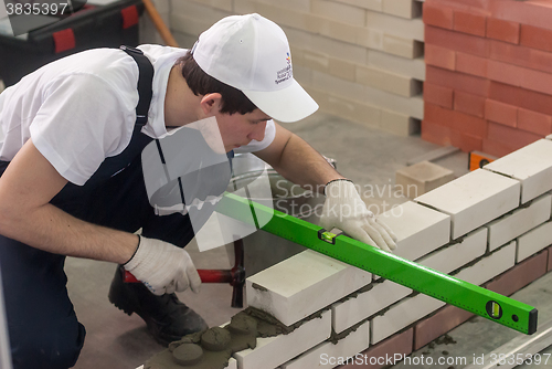 Image of Young bricklayer performs a task of competition