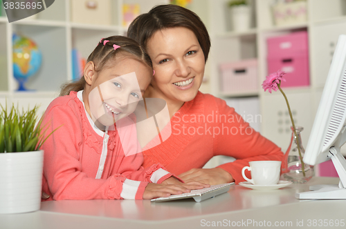 Image of little girl  with mother and computer
