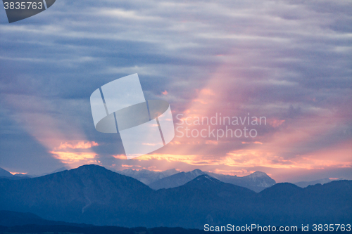 Image of First rays rising sun over dark blue morning Alps mountains