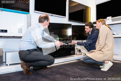 Image of Assistant Showing Flat Screen Tv To Couple In Store