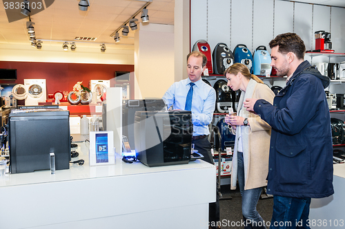 Image of Salesman Showing Espresso Maker To Couple In Store