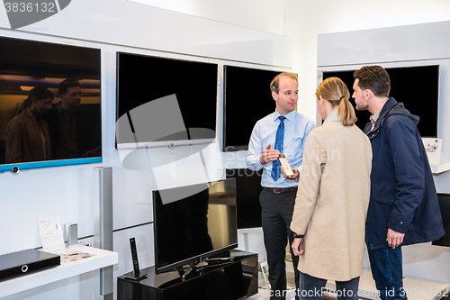 Image of Salesman Showing Flat Screen Television To Couple In Store
