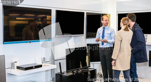 Image of Assistant Showing Flat Screen Tv To Couple In Hypermarket