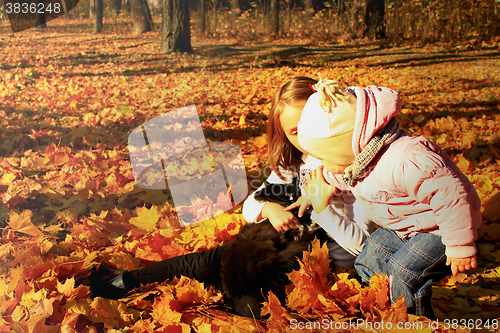 Image of little sisters play with their cat in the autumn park