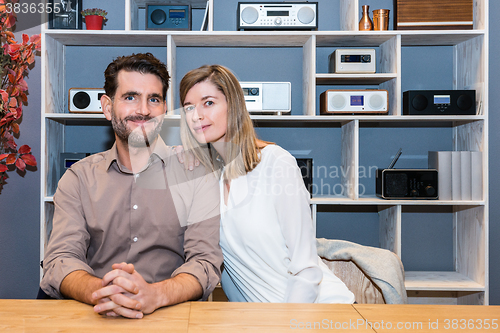 Image of Happy Couple At Counter Against Shelves With Speakers At Shop