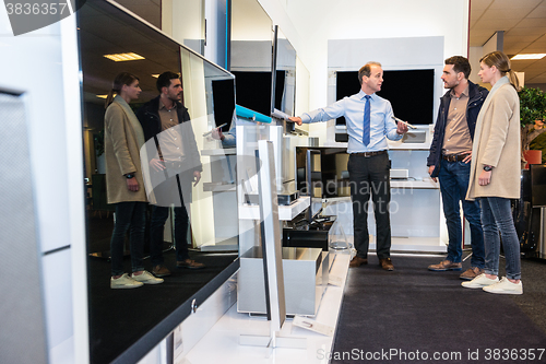 Image of Salesman Showing Flat Screen Tv To Couple In Hypermarket