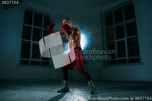 Image of The young man kickboxing in blue smoke