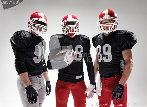 Image of The three american football players posing with ball on white background