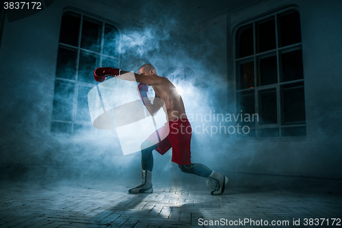 Image of The young man kickboxing in blue smoke