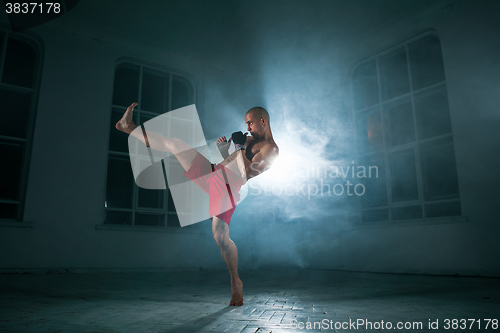 Image of The young man kickboxing in blue smoke