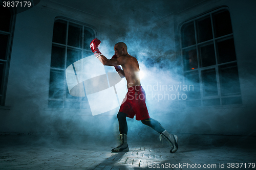 Image of The young man kickboxing in blue smoke