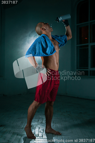 Image of The young man kickboxing on black background