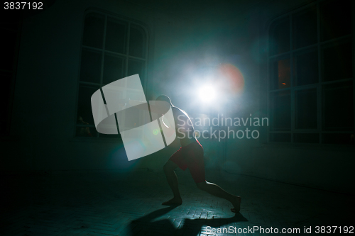 Image of The young man kickboxing on black background