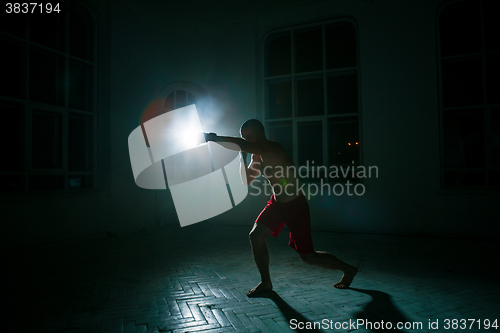 Image of The young man kickboxing on black background