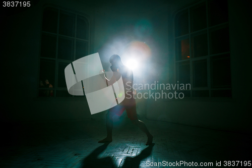 Image of The young man kickboxing on black background