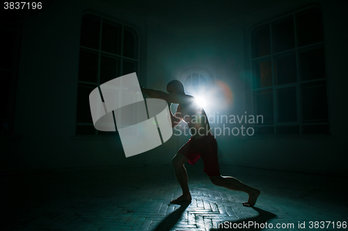 Image of The young man kickboxing on black background