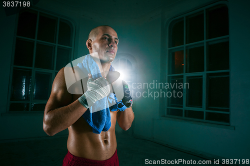Image of The young man kickboxing on black background
