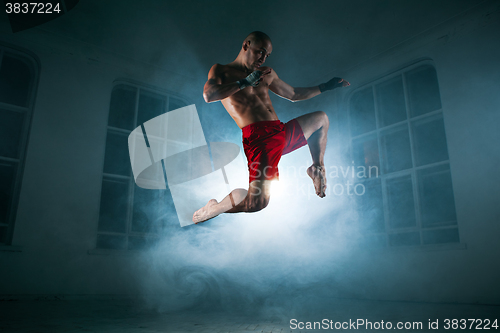 Image of The young man kickboxing in blue smoke