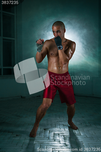 Image of The young man kickboxing in blue smoke