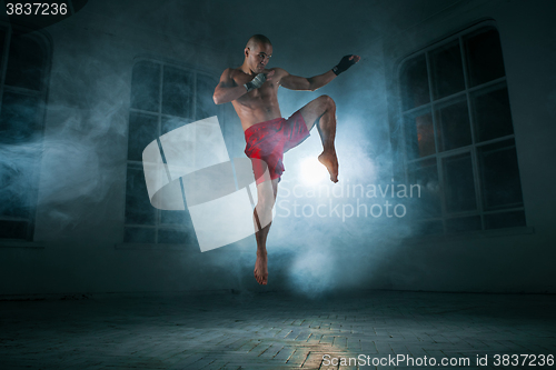 Image of The young man kickboxing in blue smoke