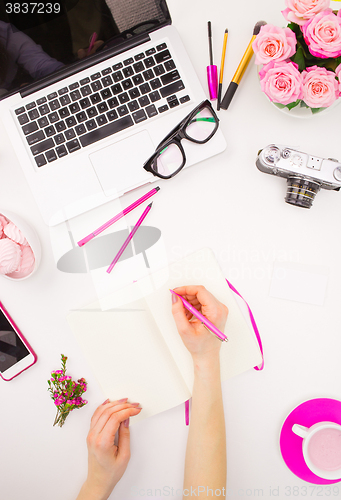 Image of The female hands writing against fashion woman objects