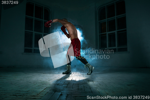 Image of The young man kickboxing in blue smoke