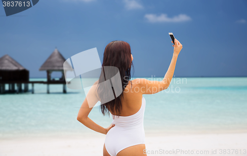 Image of young woman taking selfie with smartphone