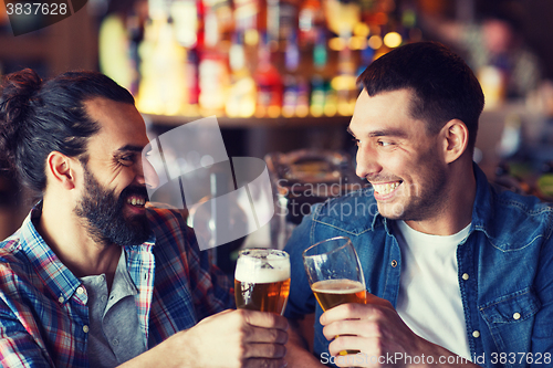 Image of happy male friends drinking beer at bar or pub