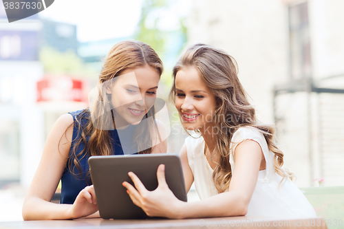 Image of happy young women with tablet pc at outdoor cafe
