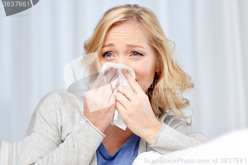 Image of ill woman blowing nose to paper napkin