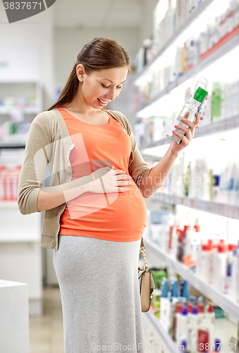 Image of happy pregnant woman choosing lotion at pharmacy