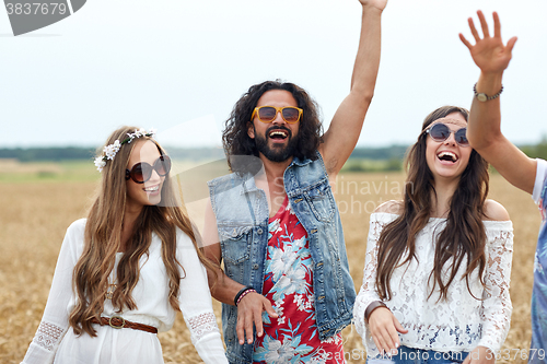 Image of happy young hippie friends dancing on cereal field