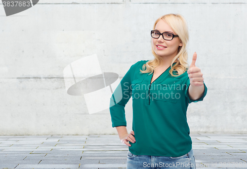 Image of young woman in eyeglasses showing thumbs up