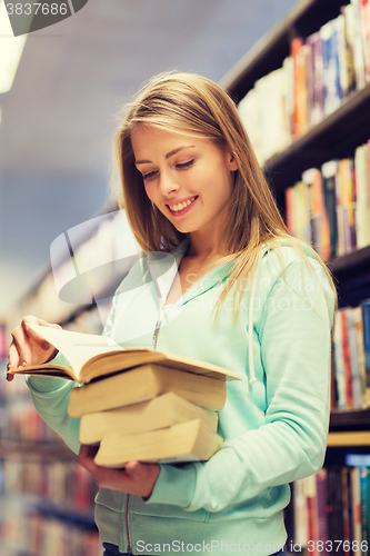 Image of happy student girl or woman with book in library