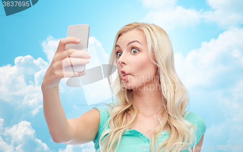 Image of funny young woman taking selfie with smartphone