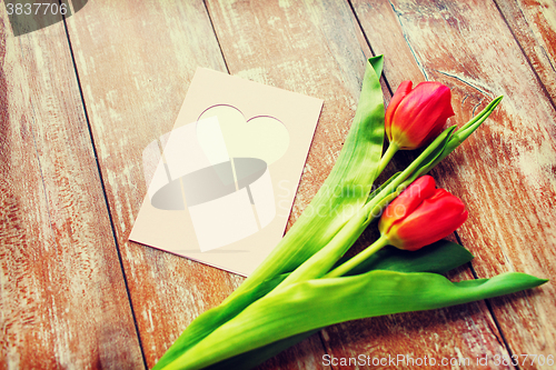 Image of close up of tulips and greeting card with heart