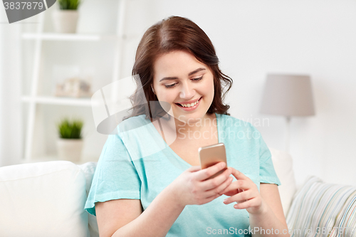 Image of happy plus size woman with smartphone at home