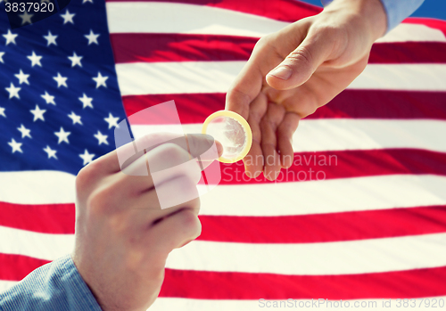 Image of close up of male gay couple hands giving condom