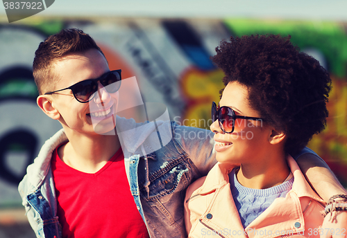 Image of happy teenage friends in shades hugging outdoors