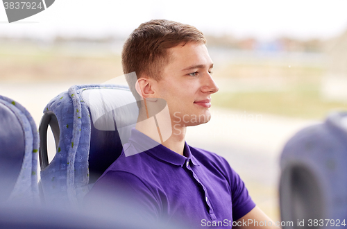 Image of happy young man sitting in travel bus or train