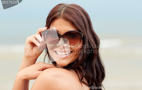 Image of smiling young woman with sunglasses on beach