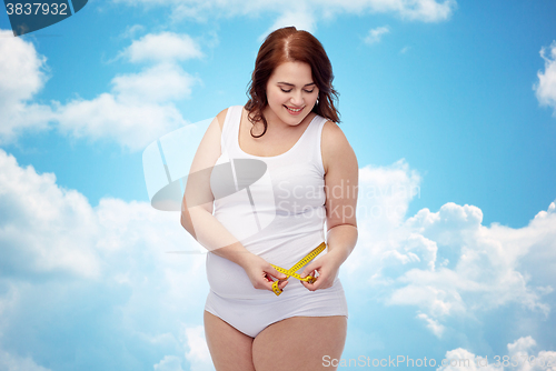 Image of happy young plus size woman with measuring tape