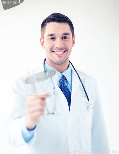 Image of young male doctor with pack of pills