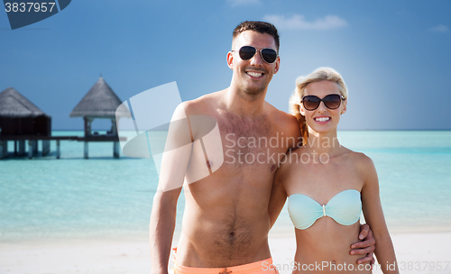 Image of happy couple in swimwear hugging on summer beach