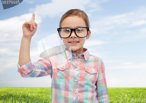 Image of happy little girl in eyeglasses pointing finger up