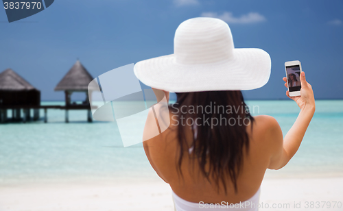 Image of smiling young woman taking selfie with smartphone